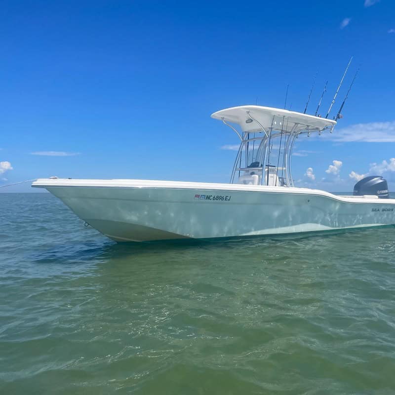 White fishing boat on the ocean under blue sky.