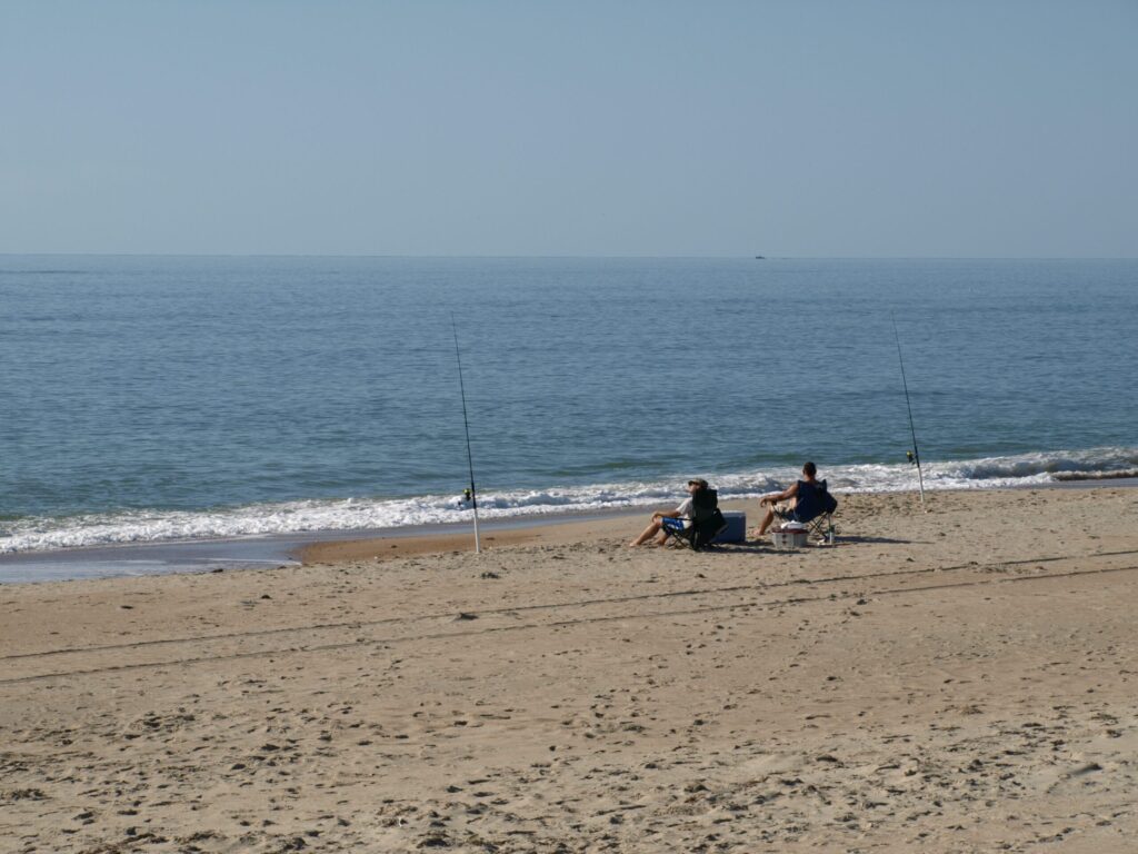 People fishing on sandy beach by the ocean