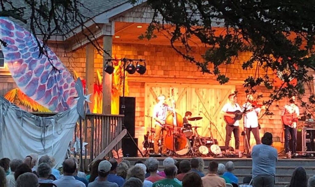 Outdoor band concert under illuminated pavilion, evening audience
