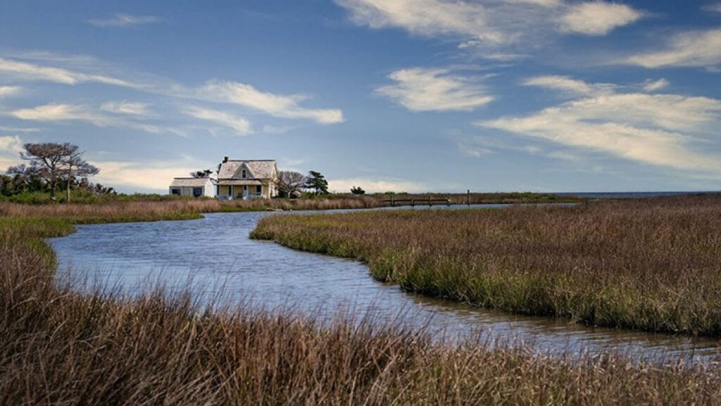 Riverside cottage under blue sky with clouds