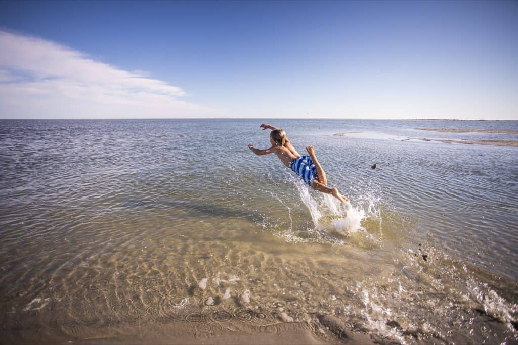 Person jumping into the sea on a sunny day.