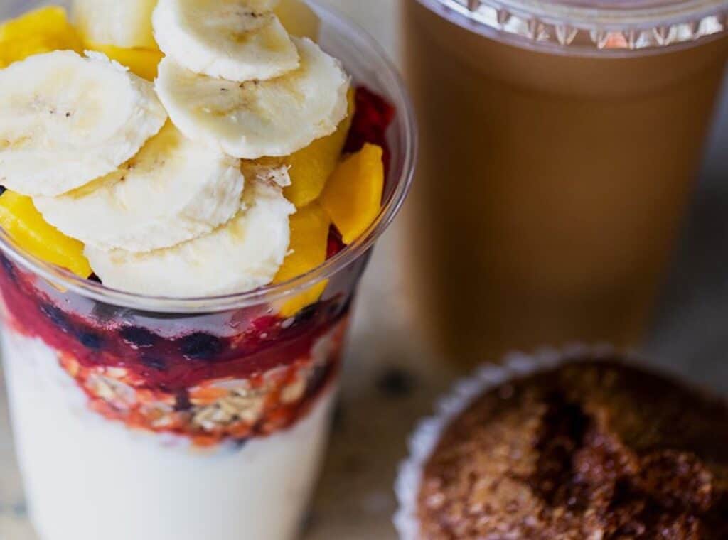 Fruit parfait with bananas and coffee cup.