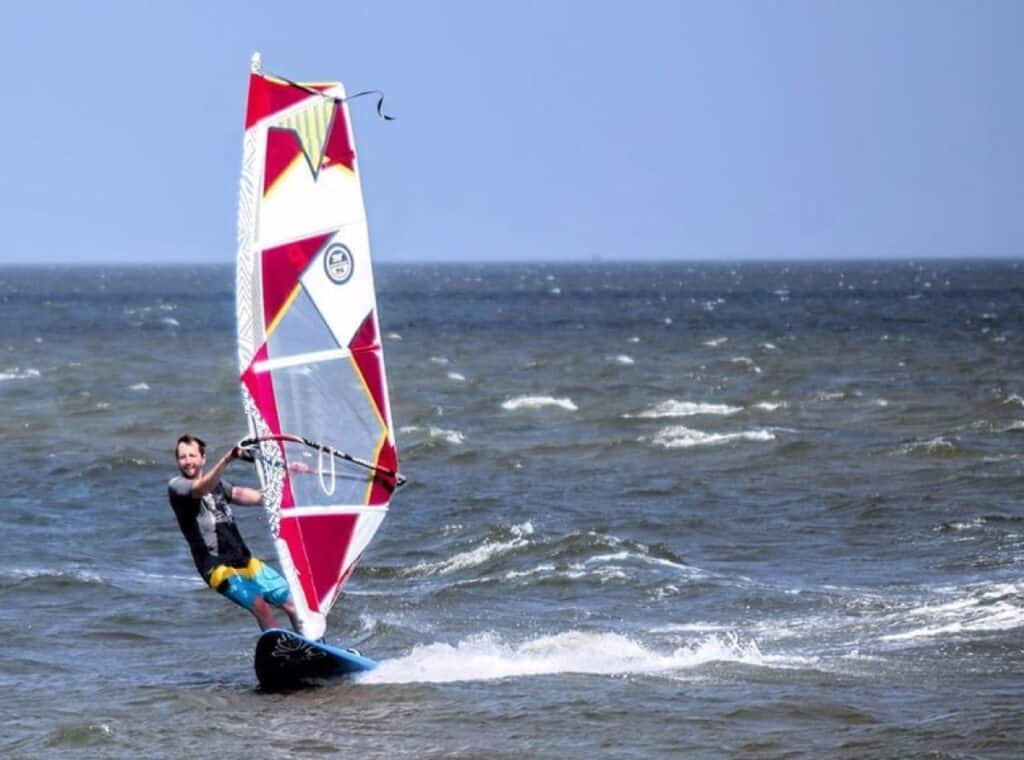 Person windsurfing on choppy ocean waves.
