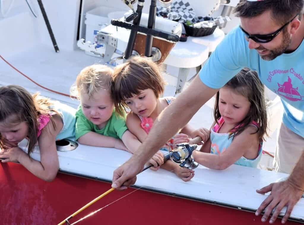 Kids fishing with adult on a boat