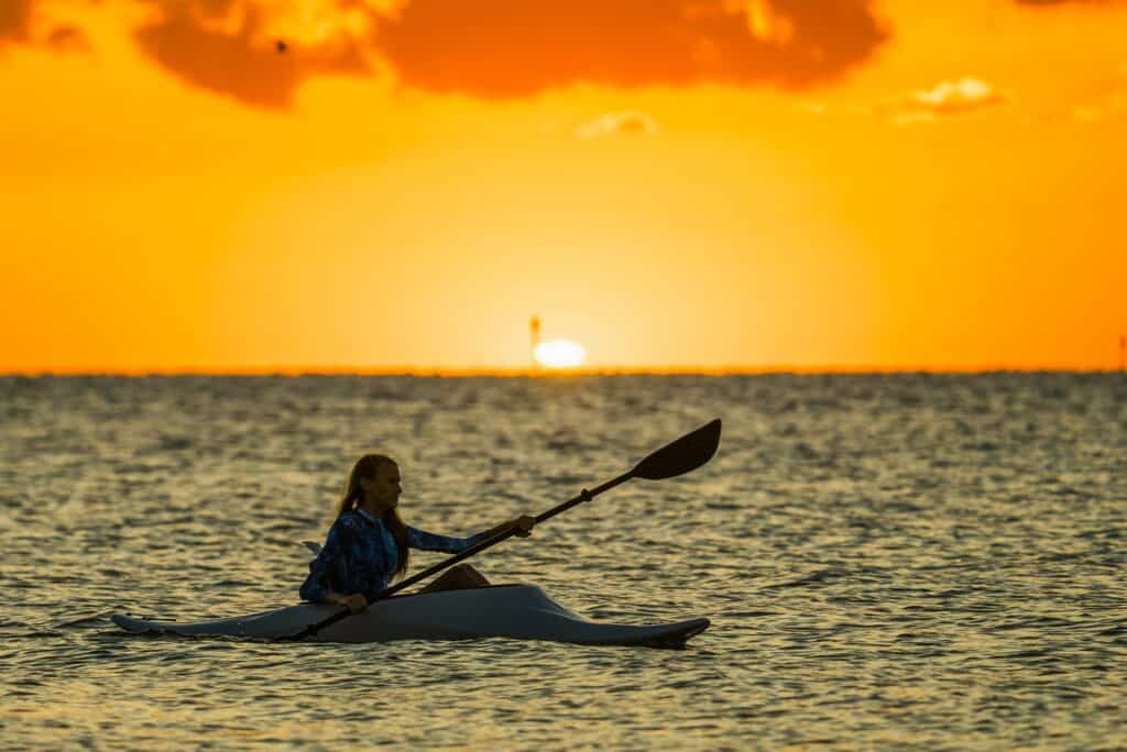Person kayaking at sunset on calm sea