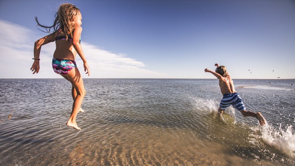 Kids playing joyfully in ocean water.