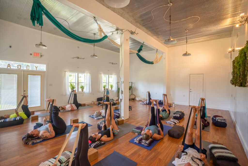 Yoga class using straps for leg stretches.
